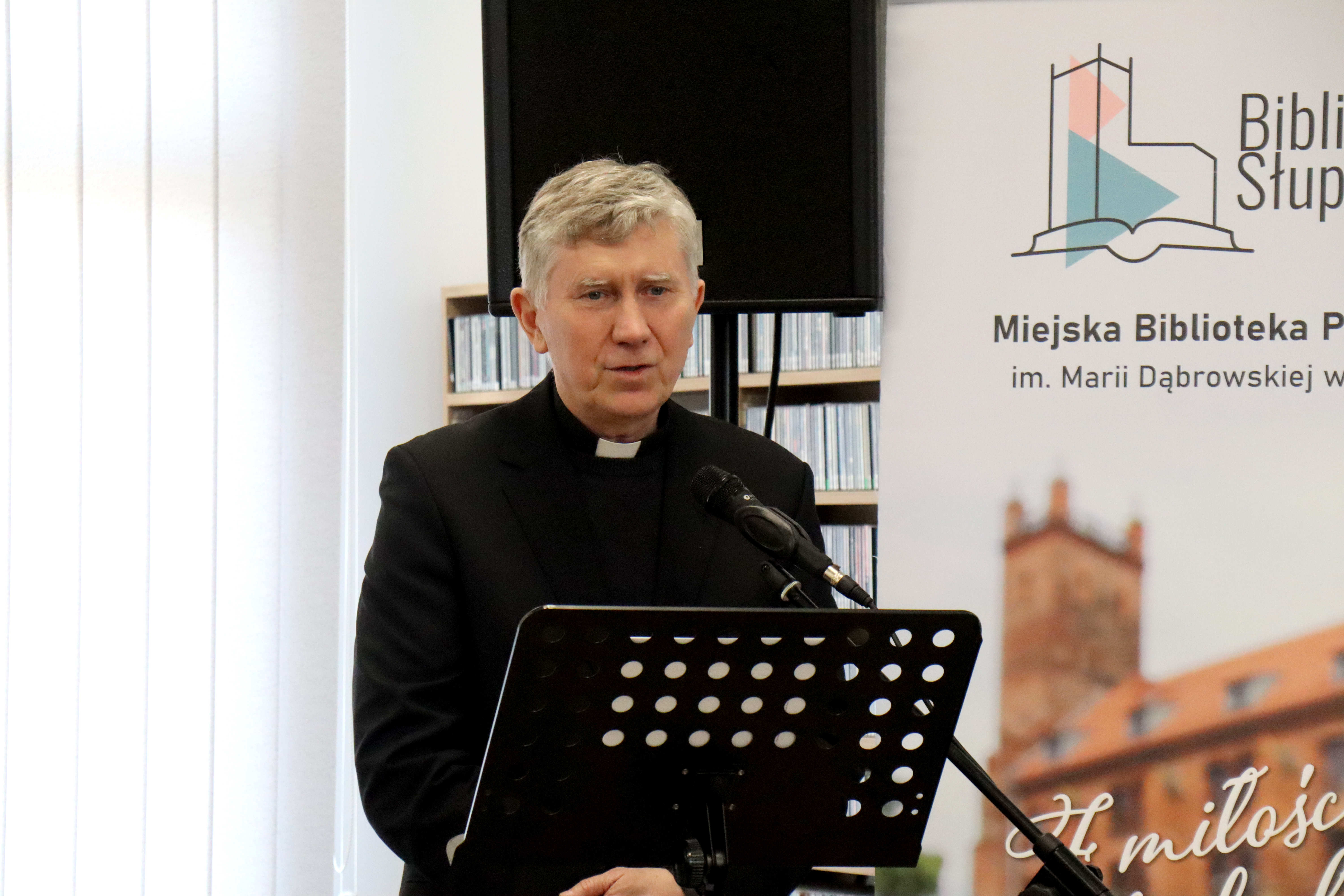 zbliżenie na postać księdza, który przemawia przez mikrofon