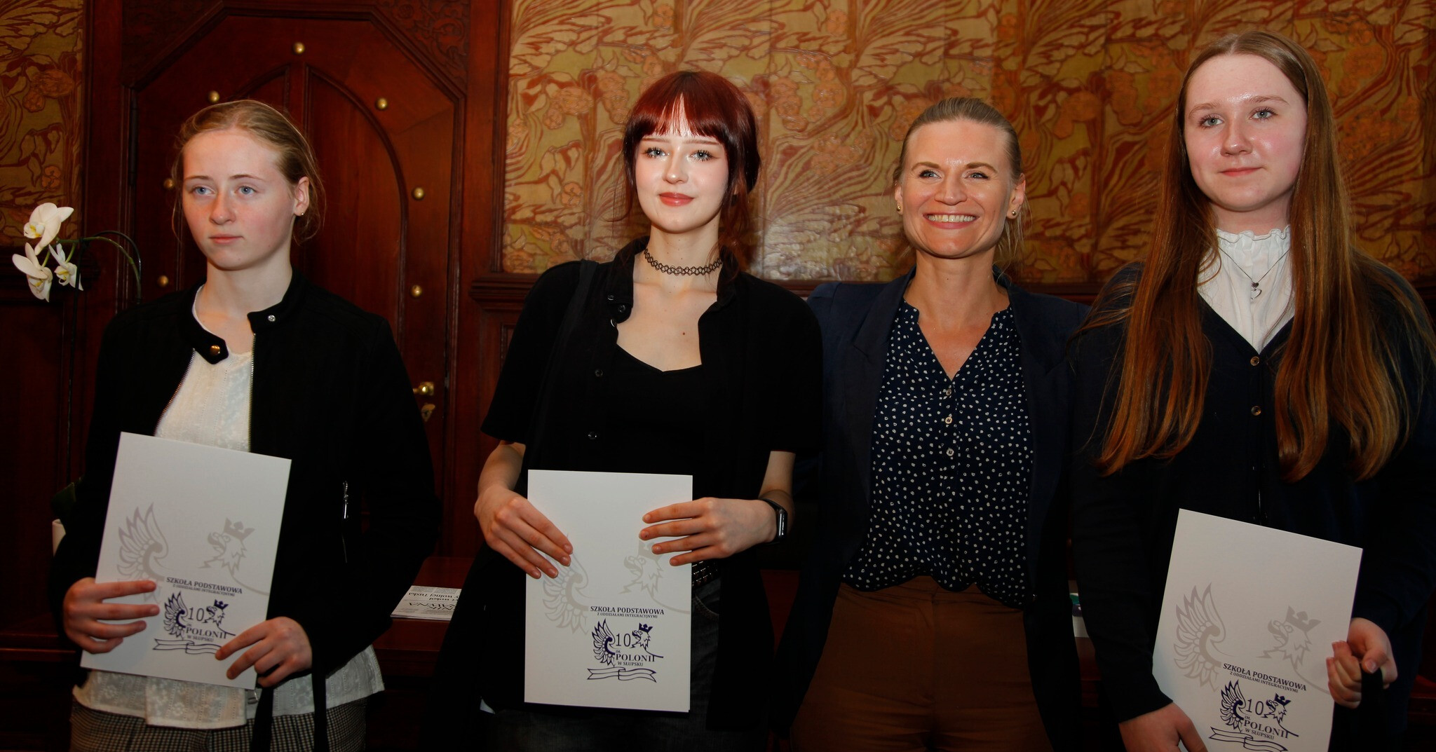 trzy nastolatki stoją z teczkami w rękach a między nimi stoi uśmiechnięta wiceprezydentka Słupska Marta Makuch