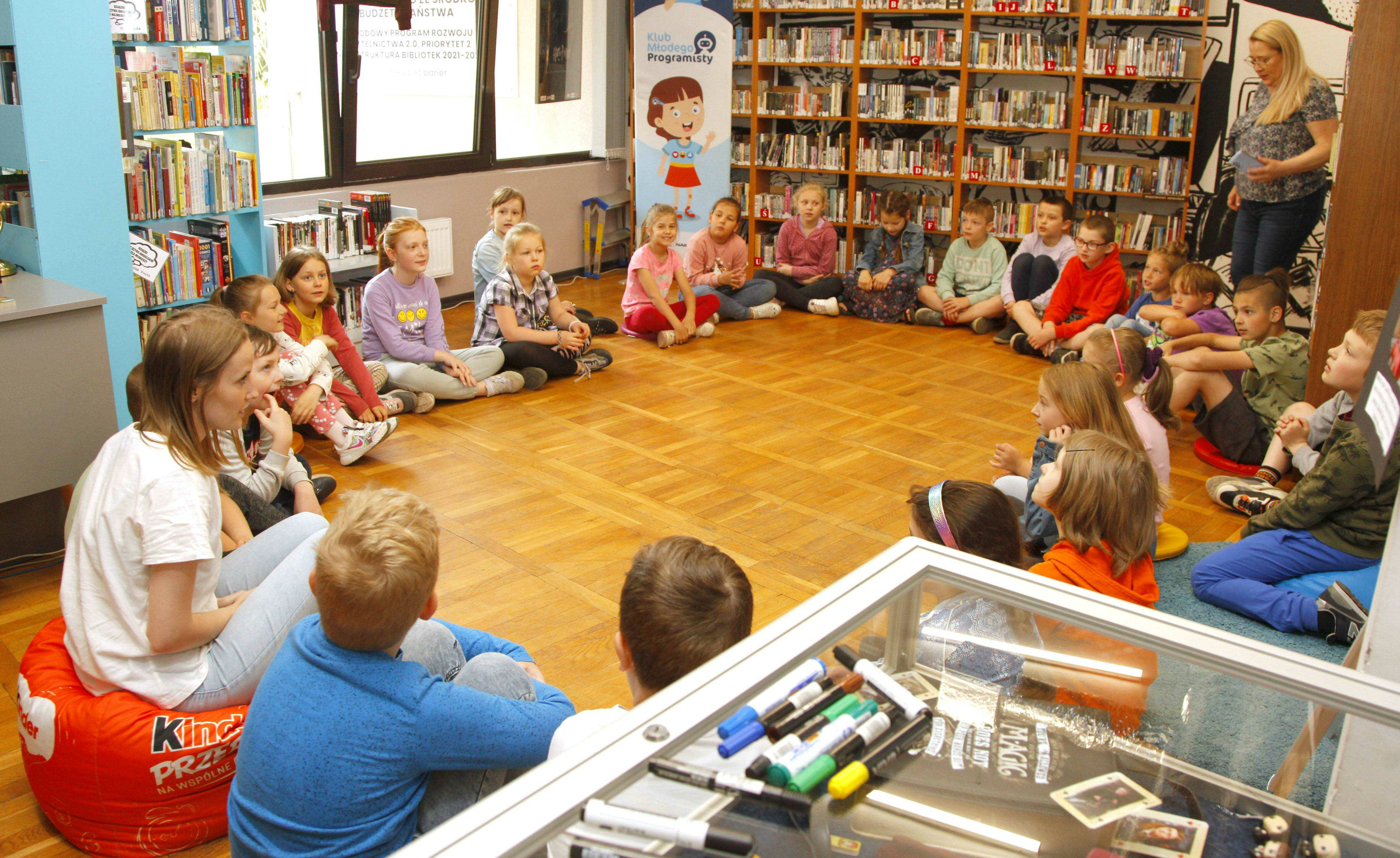 dzieci słuchają bibliotekarki opowiadającej o niezwykłych książkach