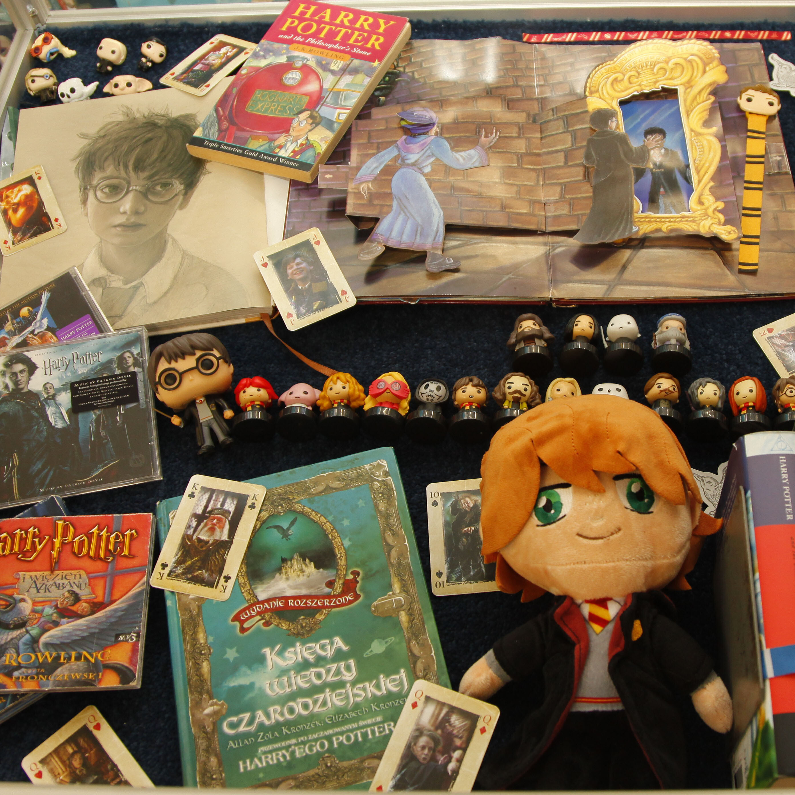 zdjęcie przedstawia przedmioty związane z Harrym Potterem: książki, karty, figurki itd.