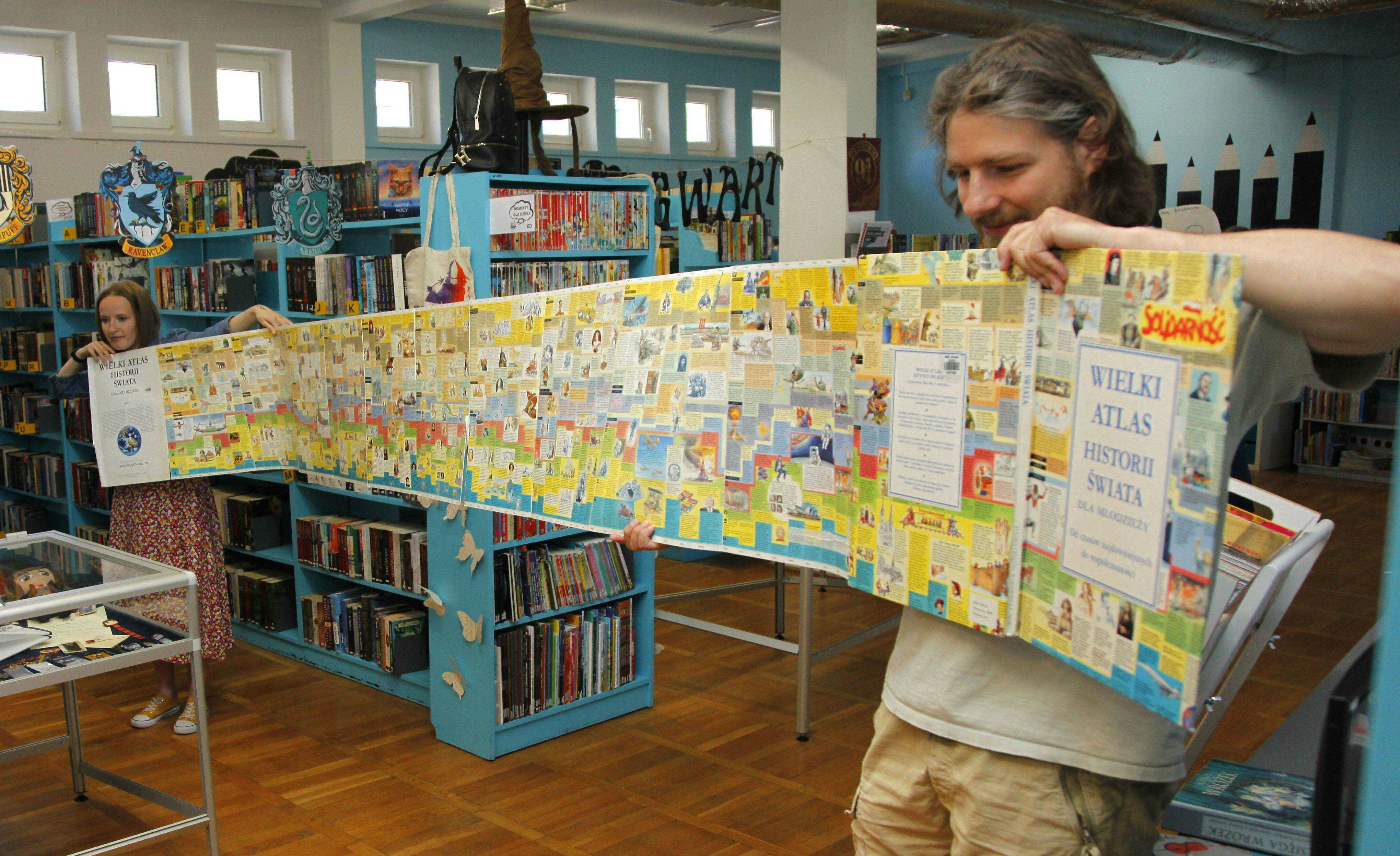 bibliotekarze prezentują rozłożoną długą książkę