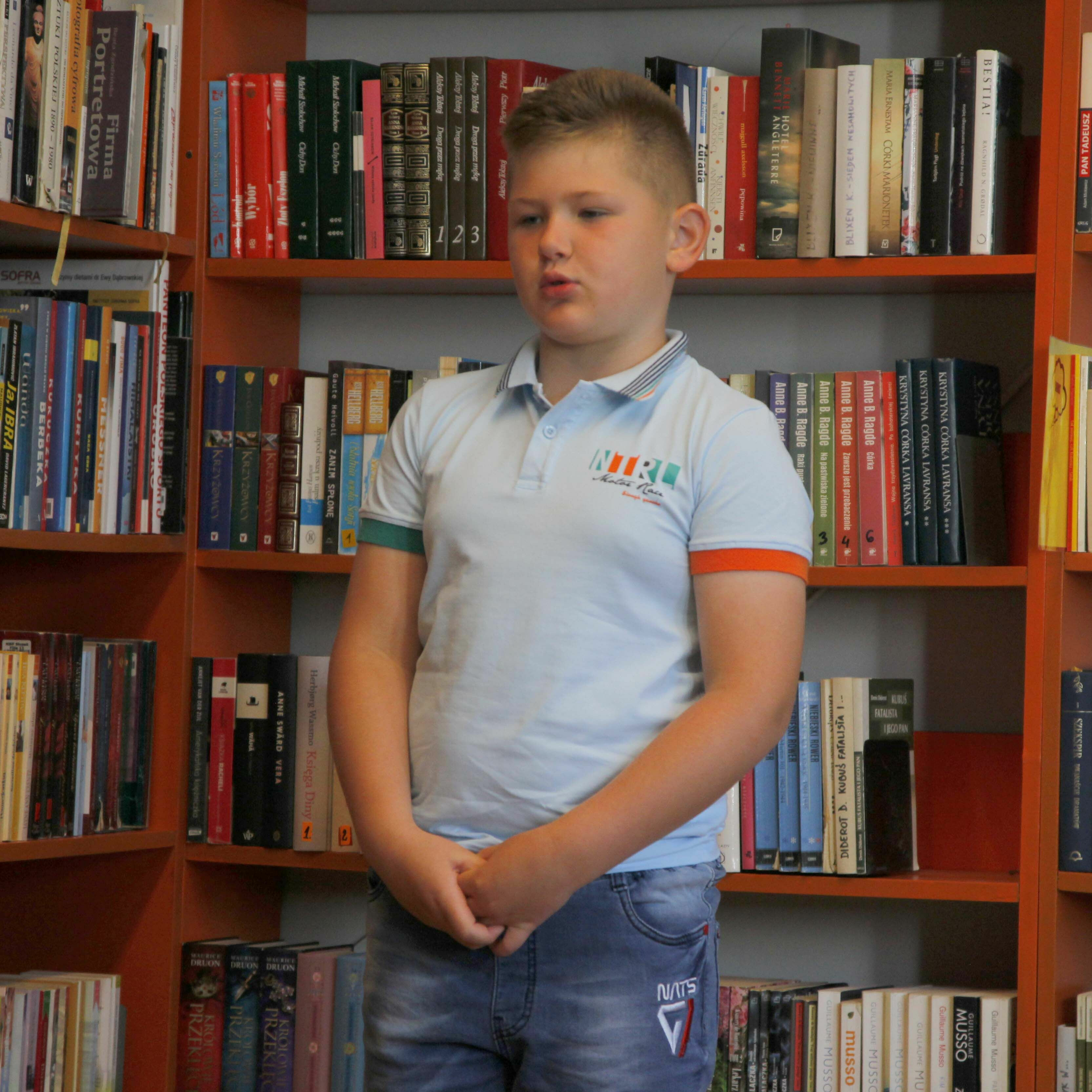 Konkurs Recytatorski - Chłopiec stojący na tle książek