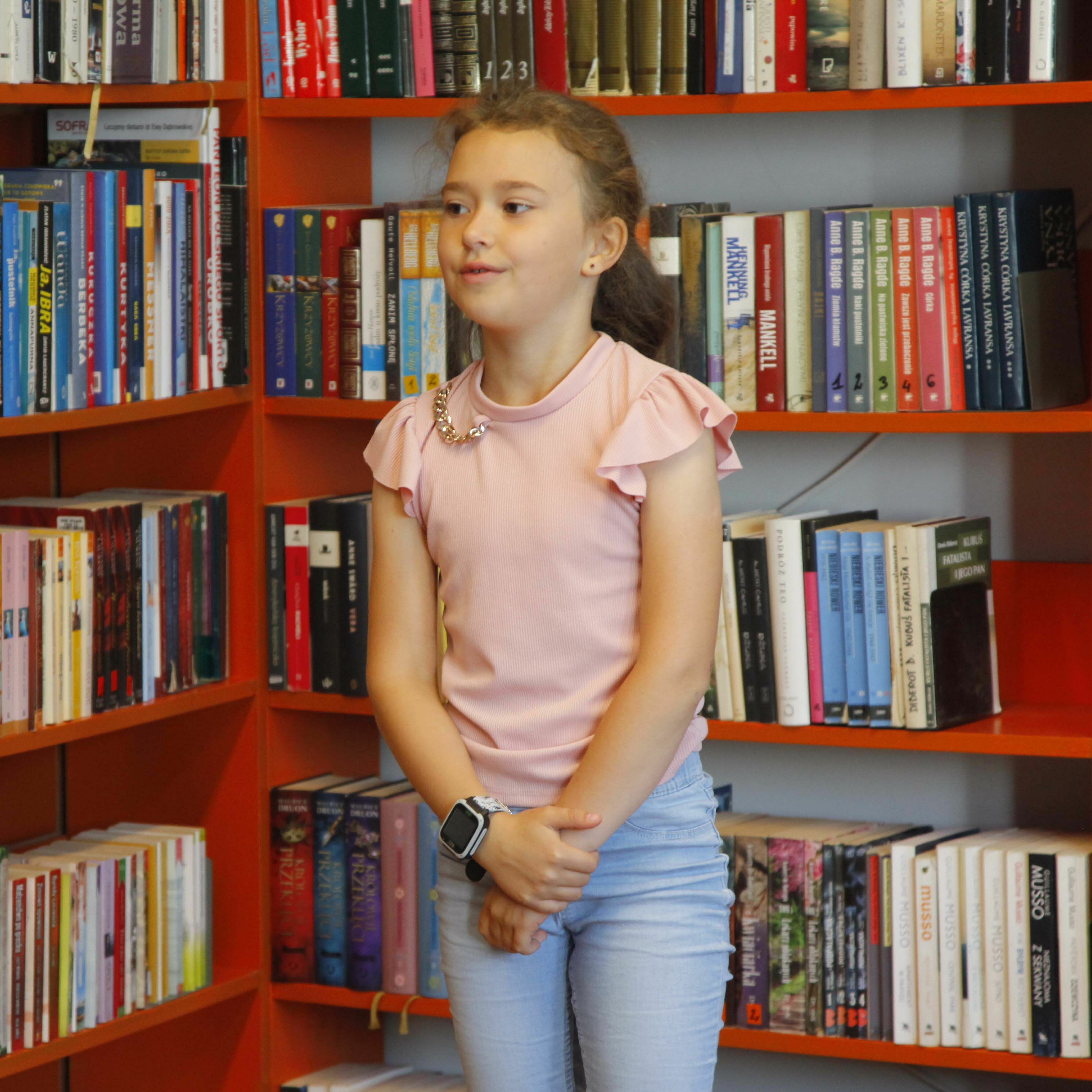 Konkurs Recytatorski - Dziewczynka stojąca na tle książek