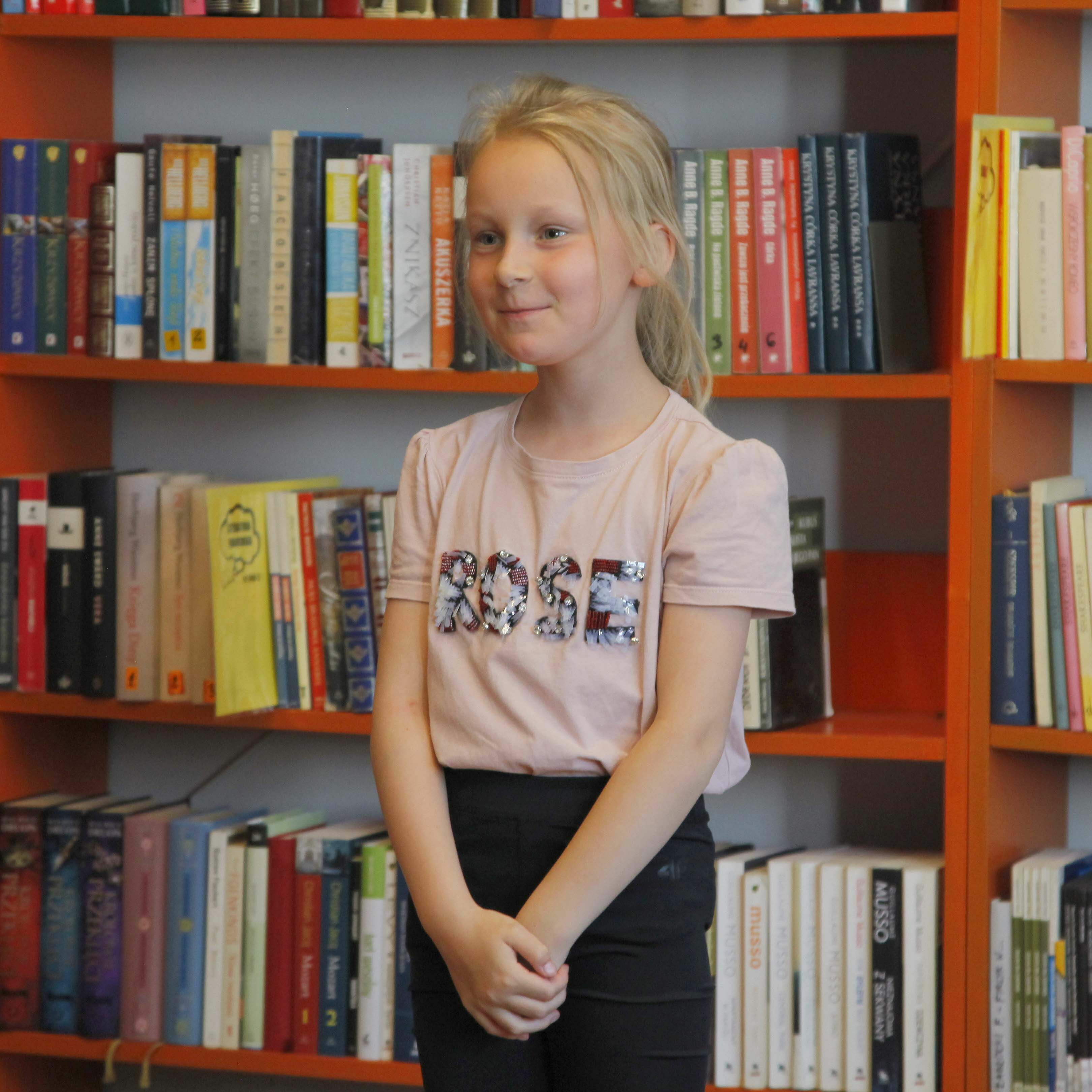 Konkurs Recytatorski - Dziewczynka stojąca na tle książek